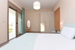 Ein Hotelzimmer mit Bett, Nachttisch mit Blumenvase, Kleiderschrank und einer Schiebetür zum Außenbereich.