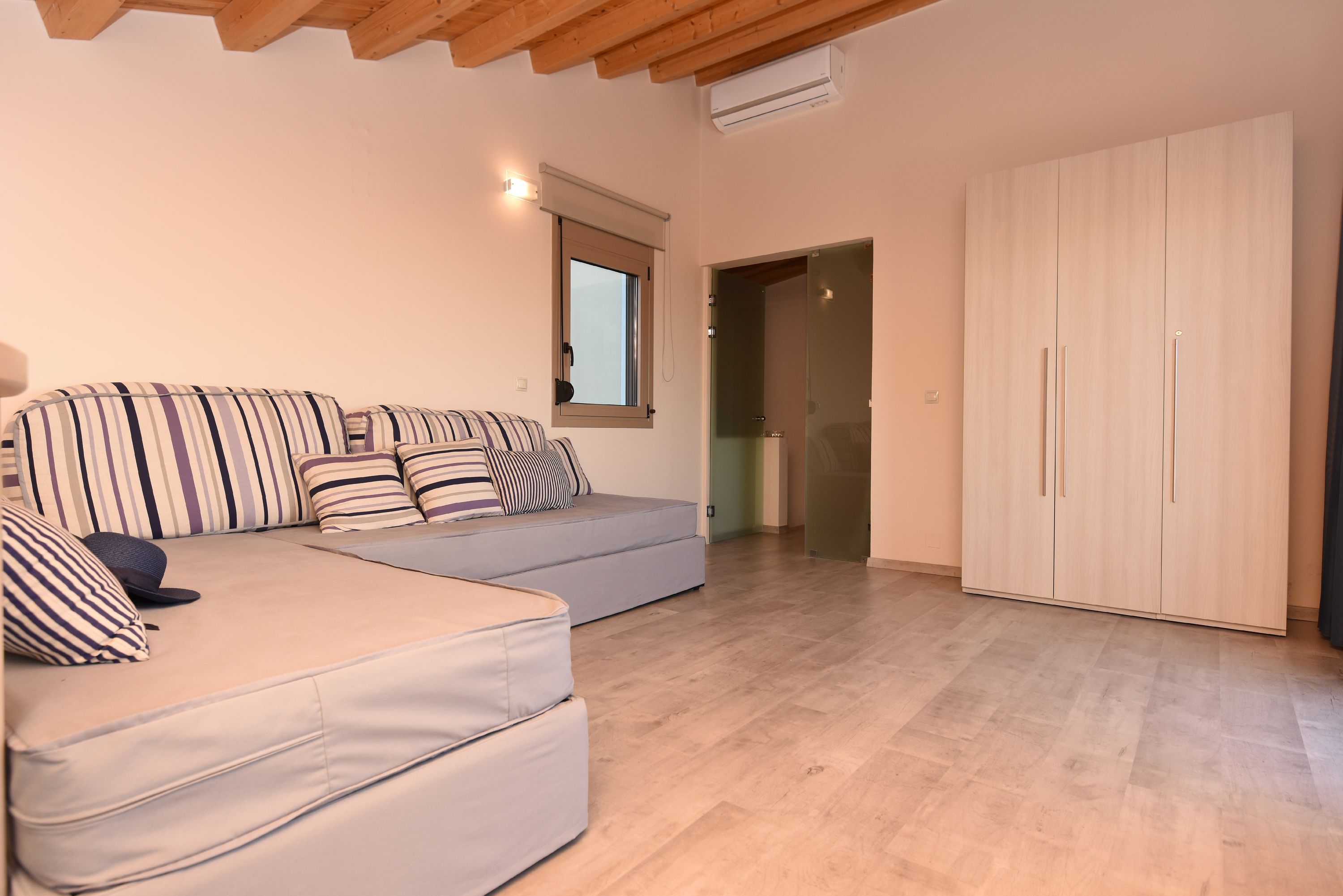 A room with a sofa set, a wardrobe, and a window.