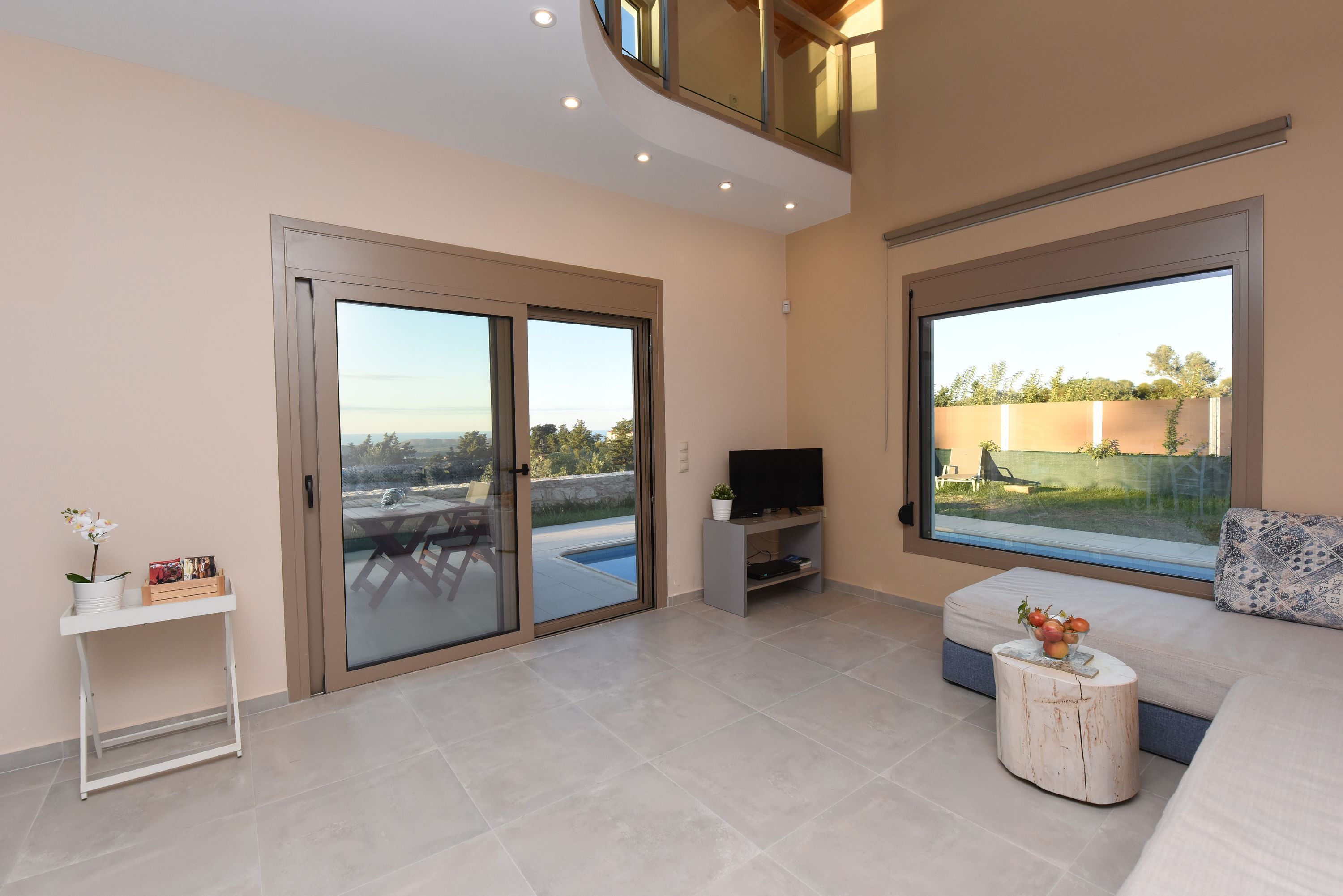 A modern living room with a pool view, a flat-screen TV, and a sofa.