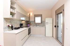 Eine kompakte Küche mit Backofen, Kaffeemaschine und Kühlschrank.