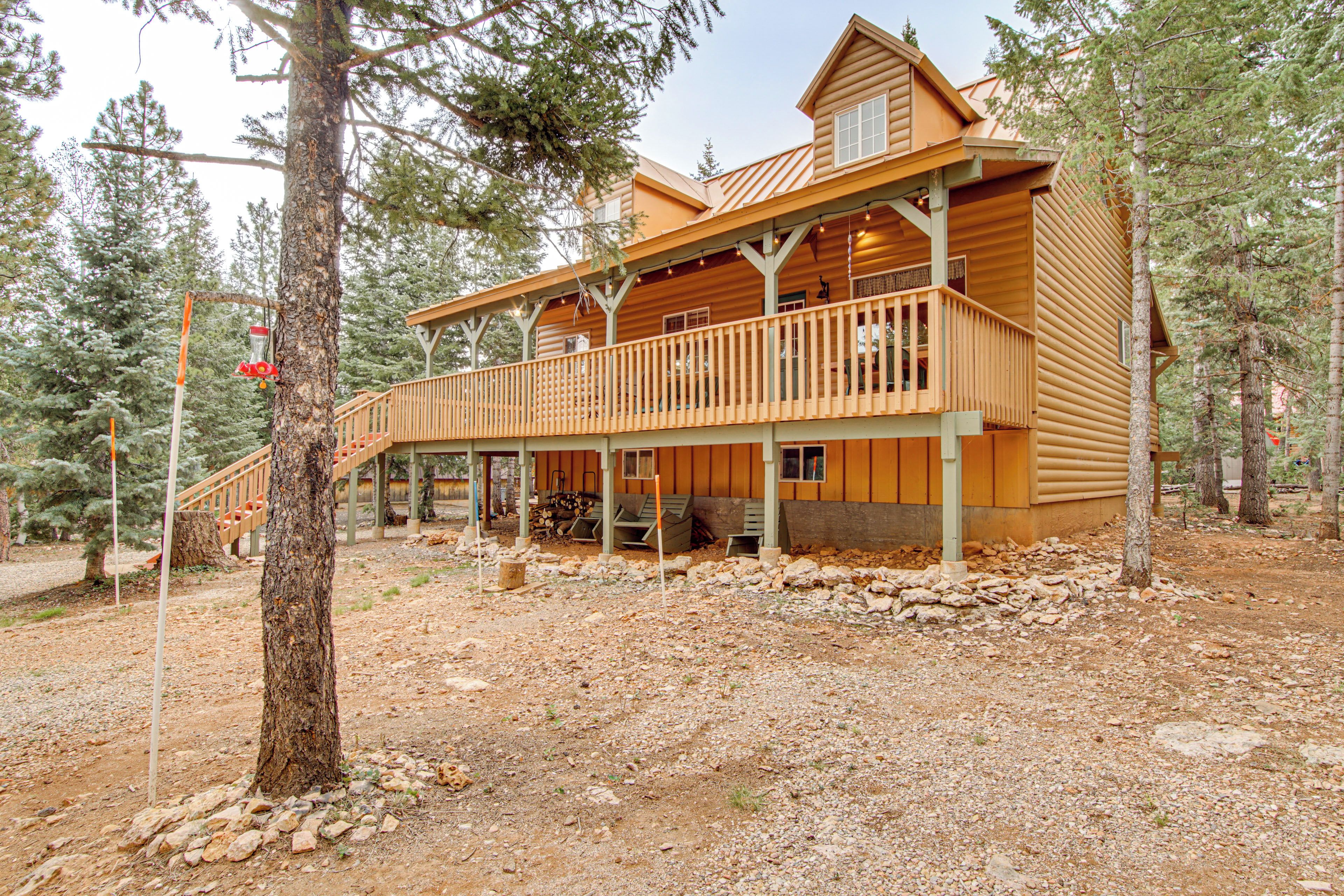 A two-story log cabin with a balcony, surrounded by trees.