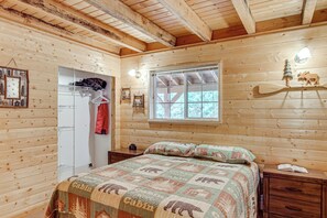 A cabin-style bedroom with a bed, a window, a coat rack, and a wall-mounted shelf. - Game Room, Fire Pit: Dog-Friendly Duck Creek Cabin (Duck Creek Village)