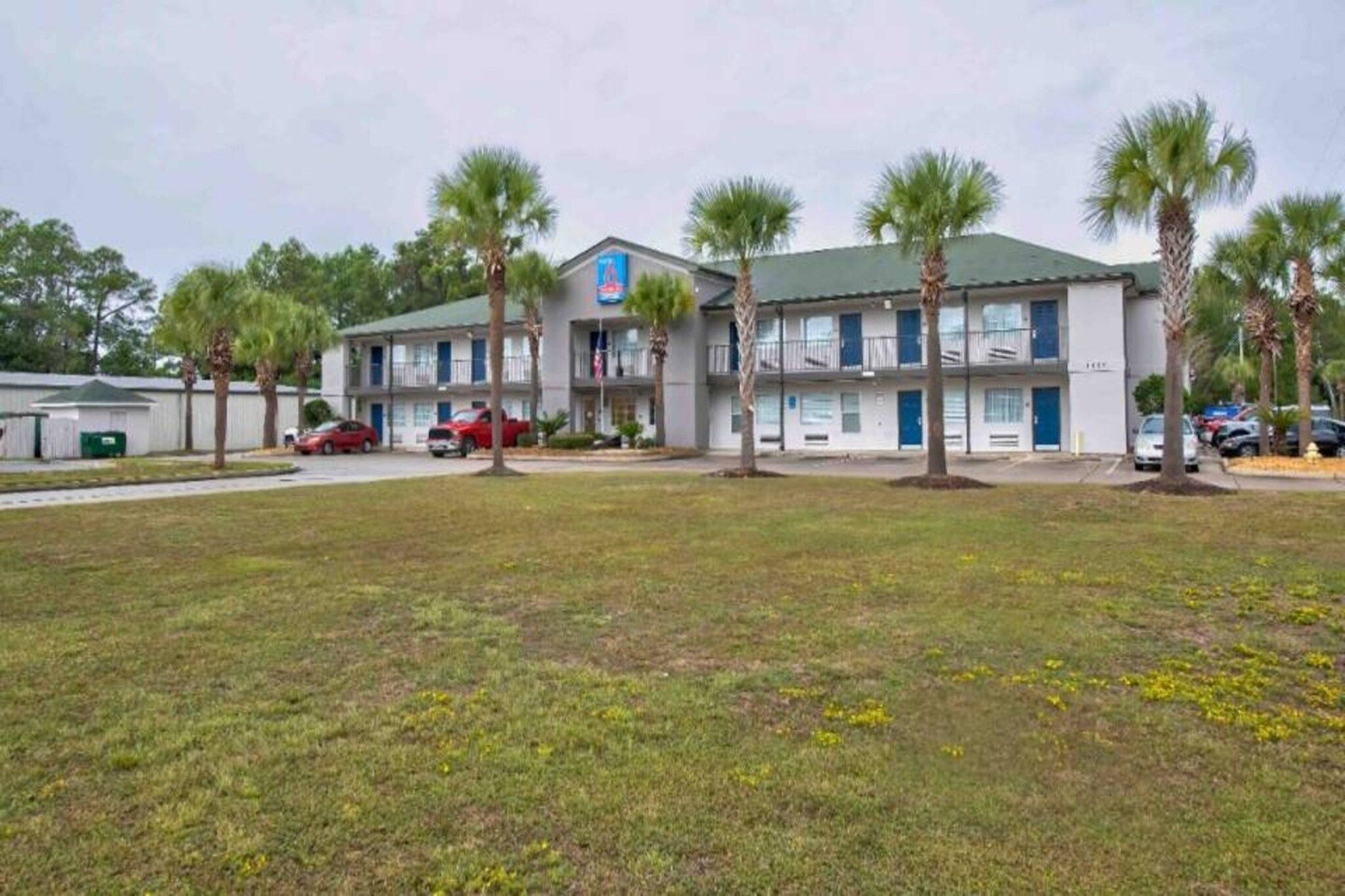 A motel with a two-story structure, multiple rooms, and a parking area with several cars.