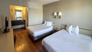 Une chambre d’hôtel avec deux lits, un bureau, un miroir et une salle de bain.