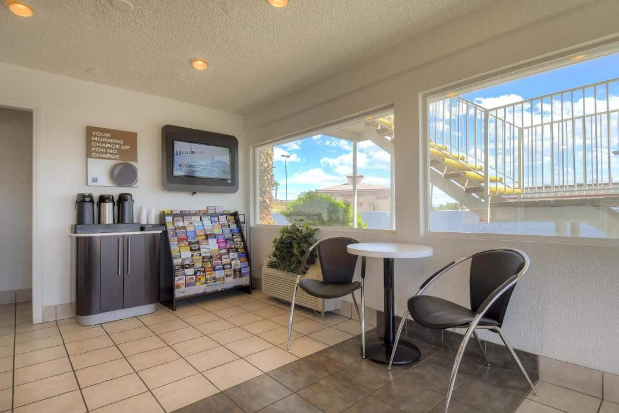 A small, clean room with a kitchenette, a television, a window with a view, and a seating area with chairs.