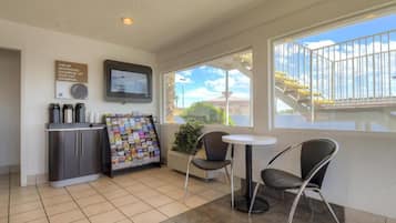 A small, clean room with a kitchenette, a television, a window with a view, and a seating area with chairs.