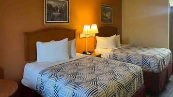 Une chambre d’hôtel avec deux lits, chacun agrémenté de draps à motifs, une table de chevet avec une lampe et des œuvres d’art encadrées accrochées aux murs.
