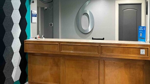A reception desk with a large number '6' sign, a door, and a blue informational sign on the wall. - 2 Queen Beds|Non-Smoking,Micfridge (Morrilton)