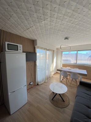 A compact living space with a kitchenette, a dining area, and a seating area. - Panoramic Sea View – Cozy Renovated Apartment (Hérault)