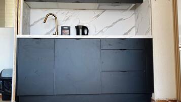 A modern kitchen with a marble backsplash, dark cabinets, and a herringbone-patterned floor.