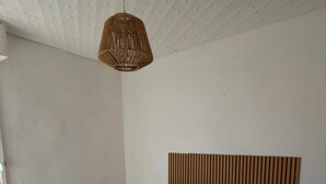 Een slaapkamer met een bed, een nachtkastje, een hanglamp en een wand met een structuur.