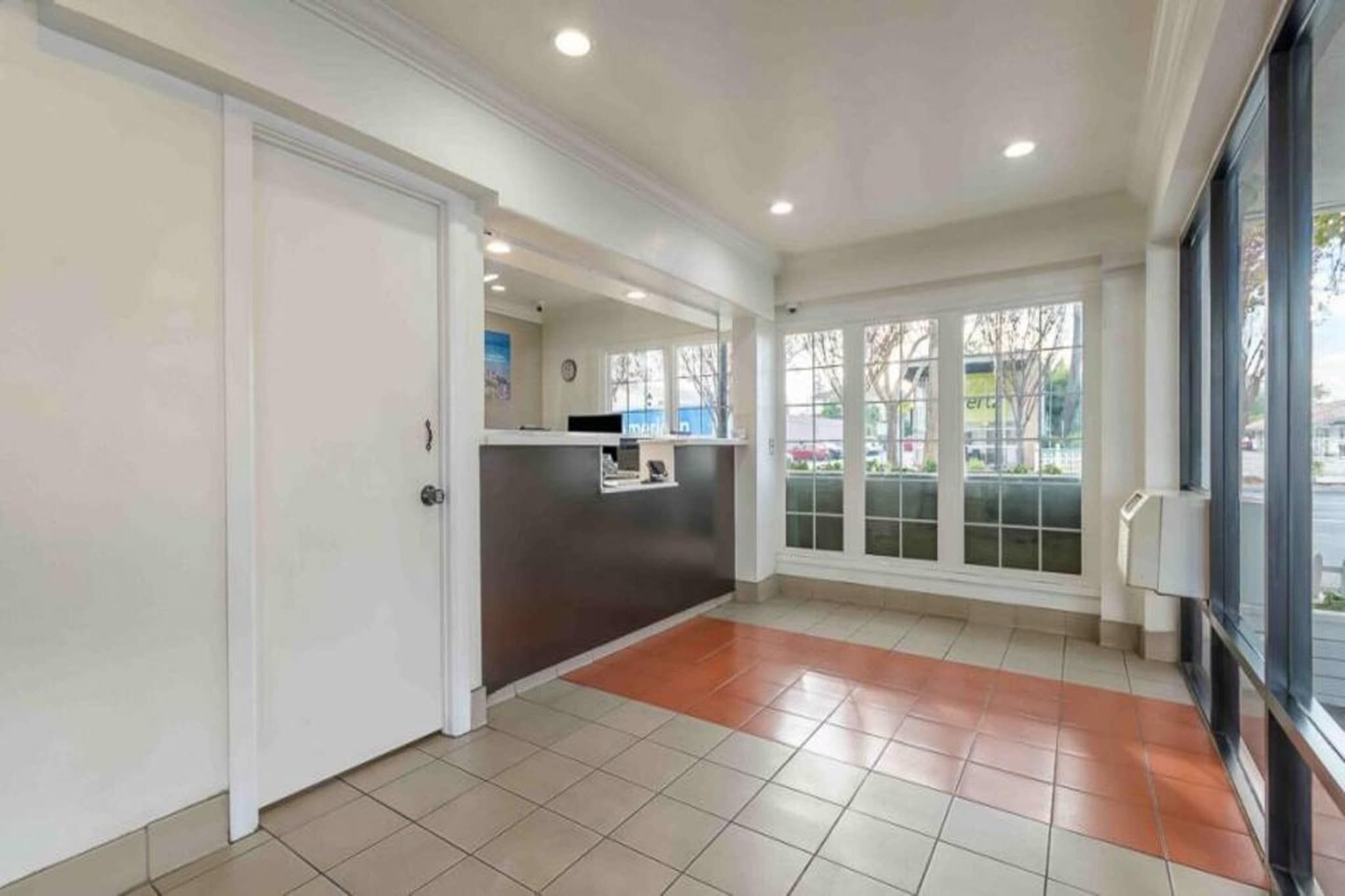 A reception area with a counter, a door, and large windows.