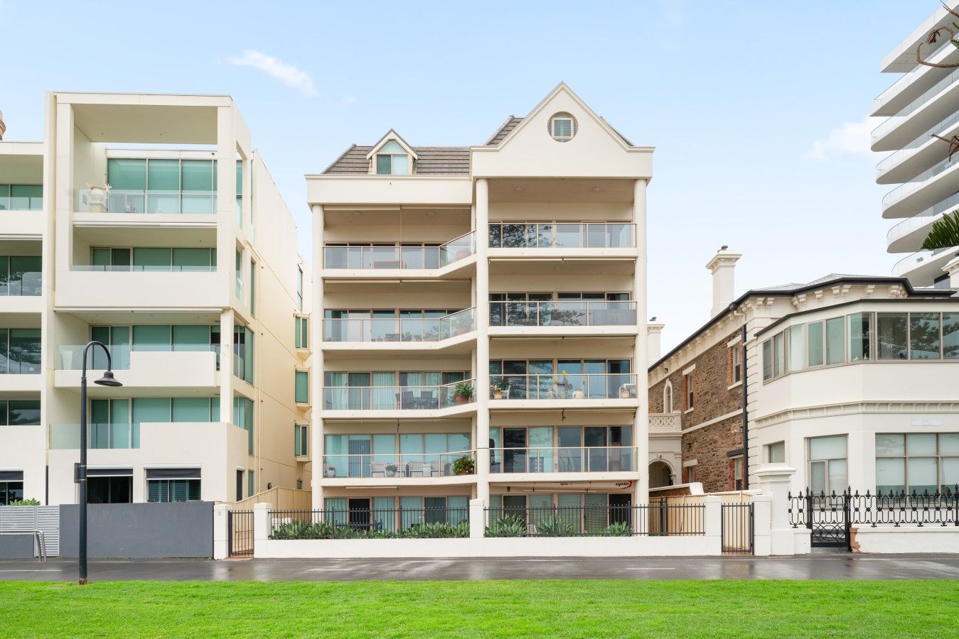 A multi-story residential building with balconies, a flat roof, and a gated entrance.
