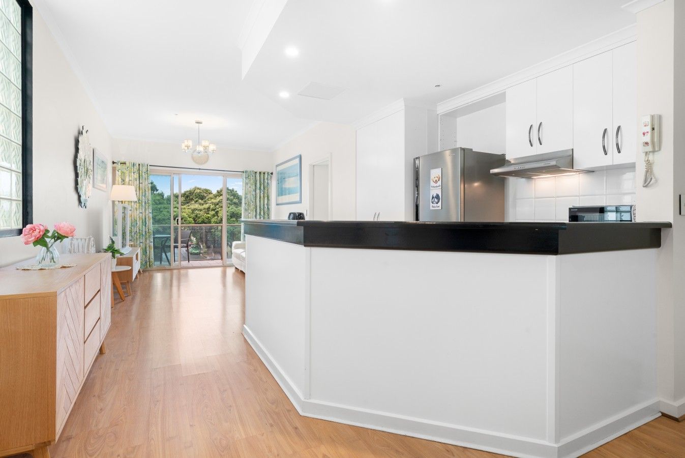 A modern kitchen with white cabinetry, a black countertop, and stainless steel appliances.