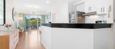 A modern kitchen with white cabinetry, a black countertop, and stainless steel appliances.