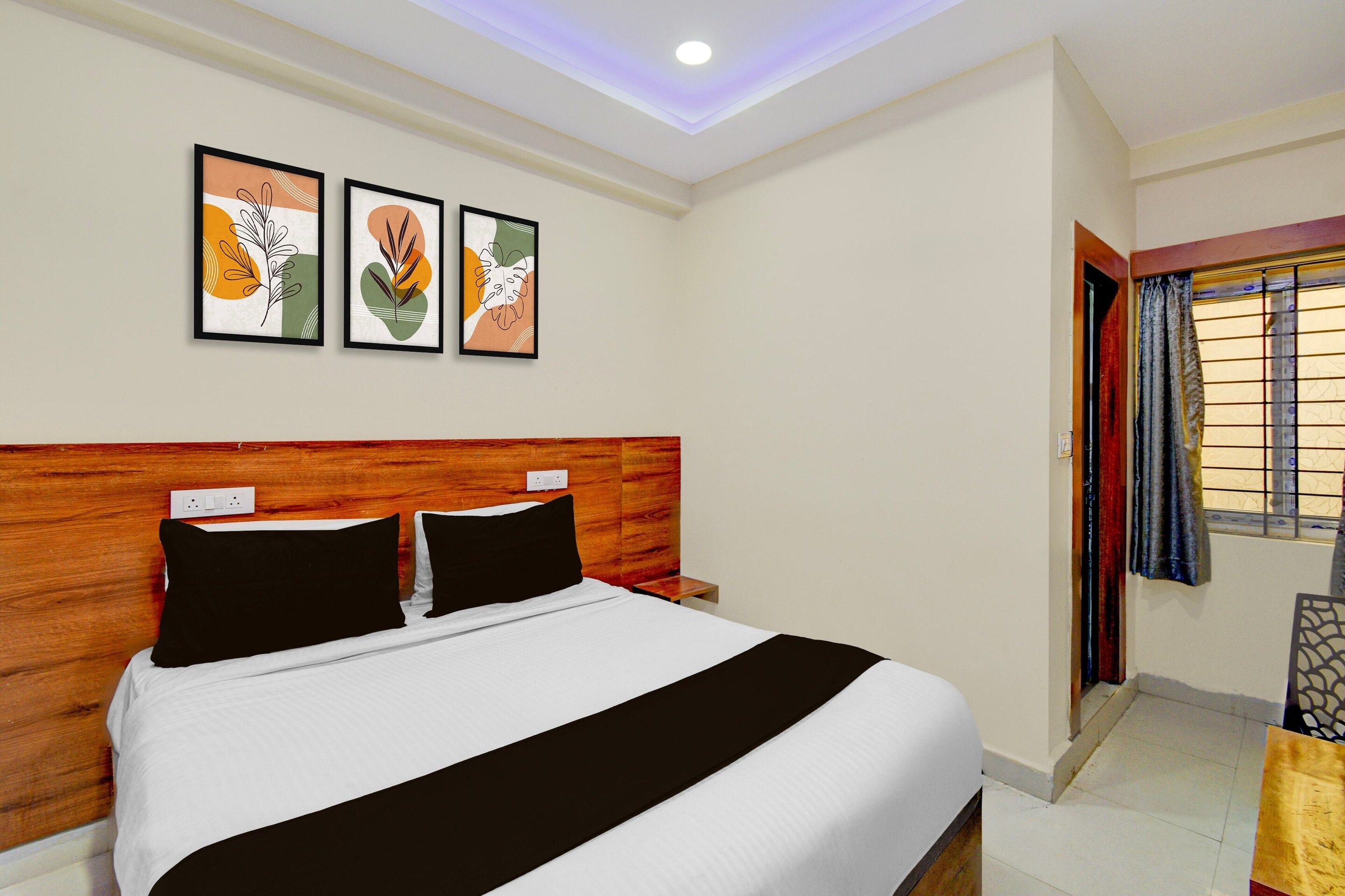A hotel room with a bed, a wooden headboard, a nightstand, and a window with curtains.