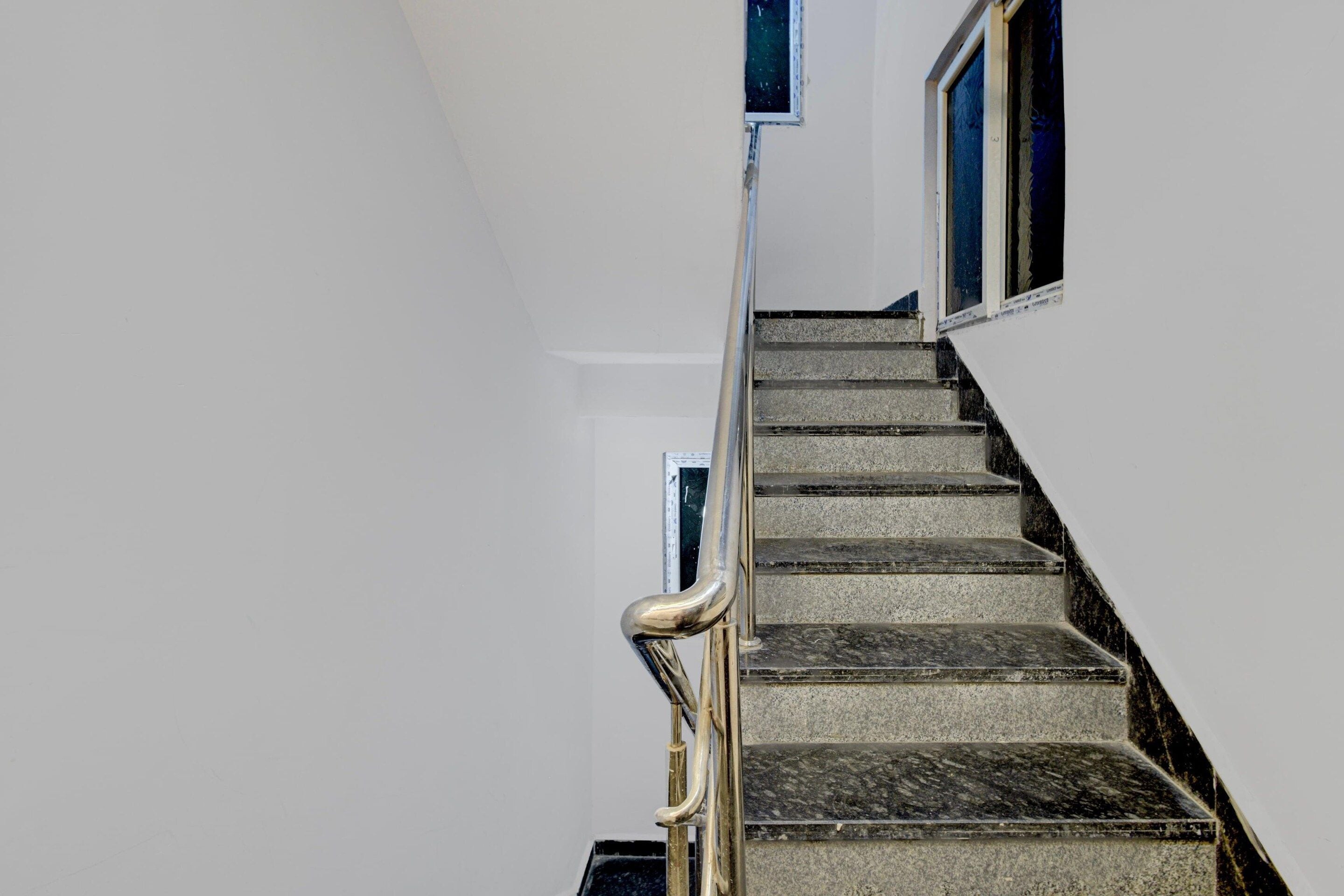 A staircase with a handrail, leading to a landing with a window.