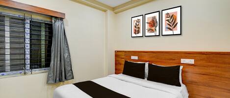 A bedroom with a bed, a window with blinds, and three framed pictures on the wall.