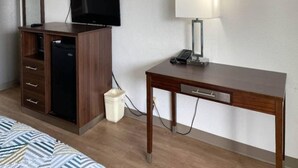 A hotel room with a wooden desk, a television, a lamp, and a trash bin. - 1 King Bed|Smoking|Opelika, AL (Opelika AL)