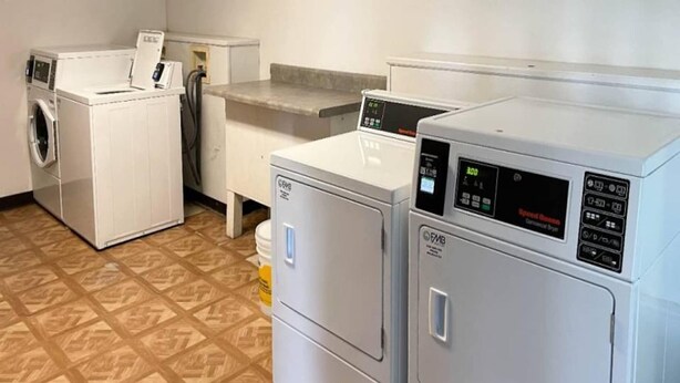 A laundry room with a front-loading washer, a top-loading dryer, and a countertop with a sink. - 1 King Bed|Smoking|Opelika, AL (Opelika AL)