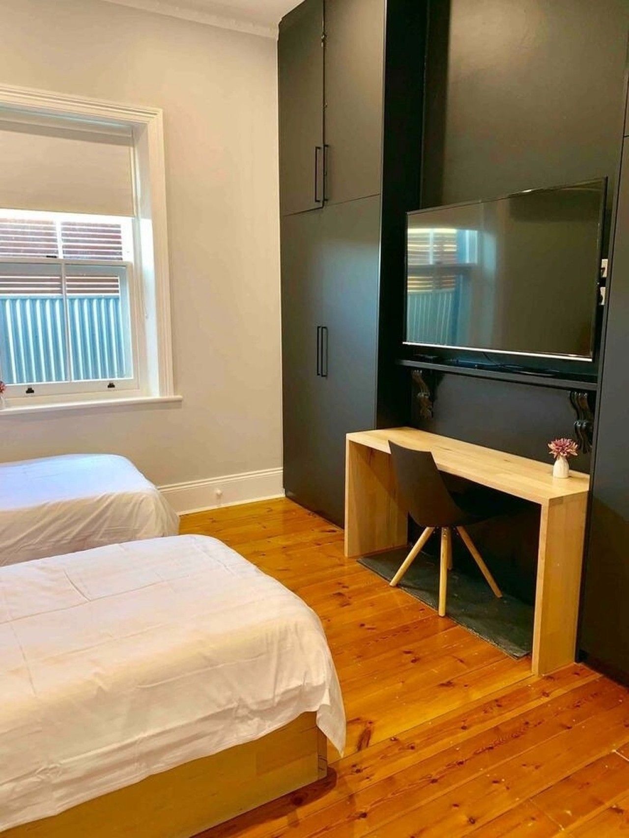 Quarto com duas camas, uma escrivaninha e uma televisão.