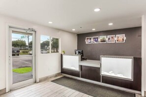 A reception area with a desk, a computer, and a wall-mounted photo display. - Cozy Queen Bed ADA Room|Free Wifi (Jacksonville)