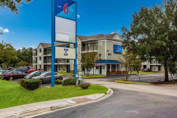 A motel with a sign indicating 6 rooms at $49.99. - Cozy Queen Bed ADA Room|Free Wifi (Jacksonville)