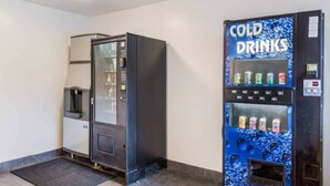 Een automaat met een blauwe buitenkant en de tekst 'COLD DRINKS', en een andere automaat met een glazen deur.