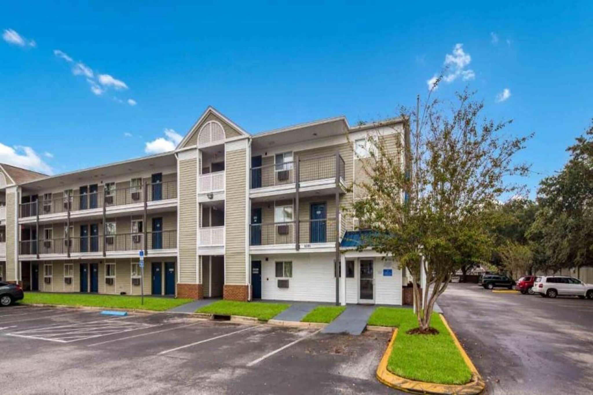 A multi-story apartment building with a parking lot in front.