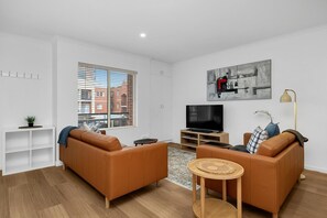 Ein modernes Wohnzimmer mit zwei Sofas, einem Fernseher und einem Gemälde an der Wand.
