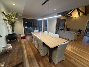 A spacious dining area with a large wooden table and striped chairs, a potted plant, and a black pot on the floor. - Willenber Farm – Historic Farmhouse Escape (Megalong Valley)