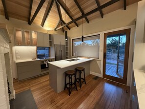 Une cuisine moderne avec un îlot central, des tabourets de bar et une grande fenêtre.