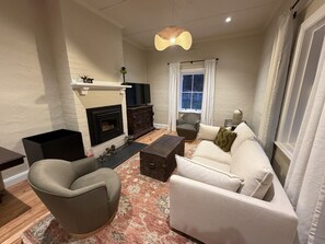 Un salon avec une cheminée, un canapé, un fauteuil et un tapis décoratif.