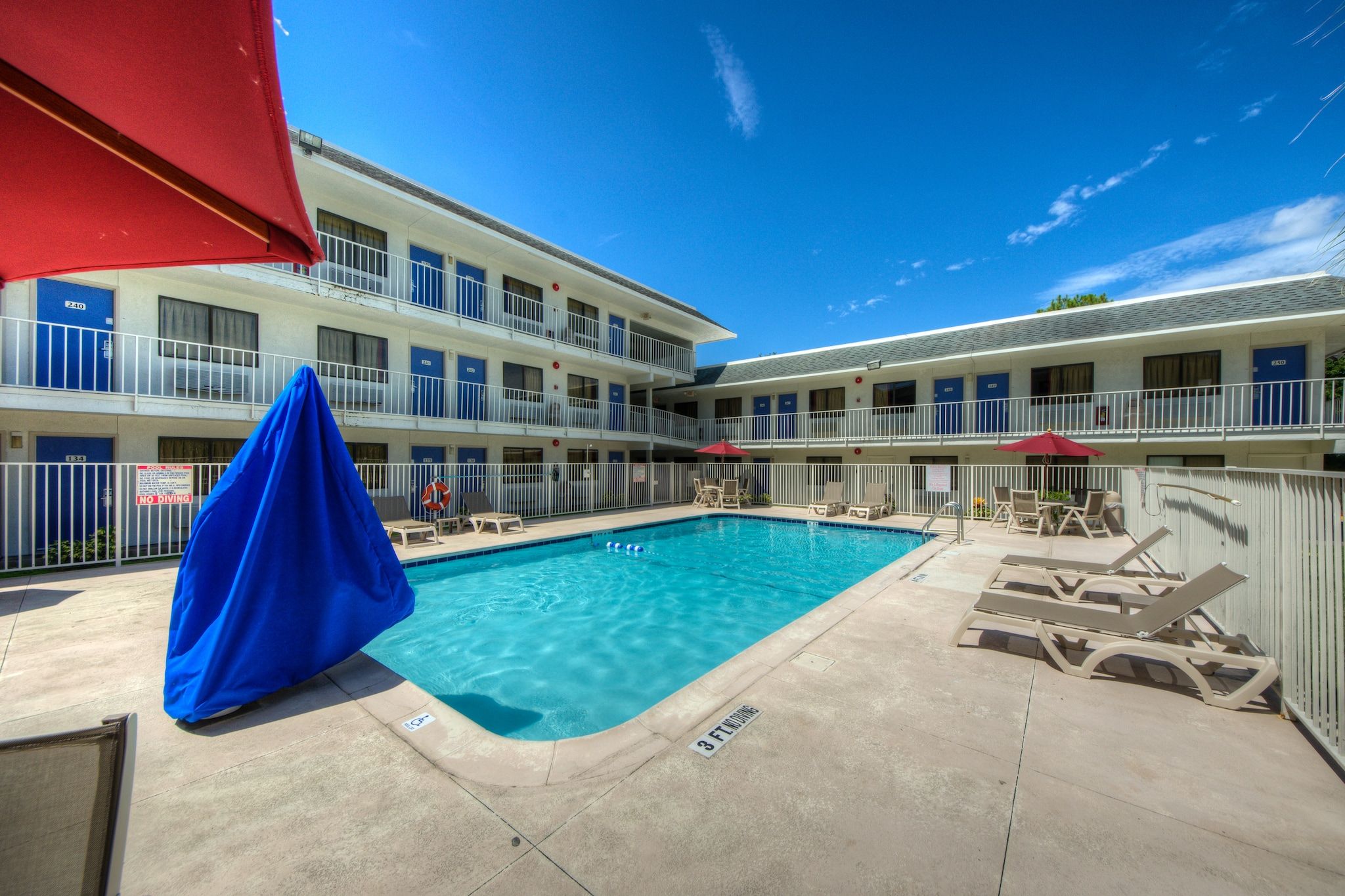 A pool area with a clear blue pool, lounge chairs, and a covered seating area.