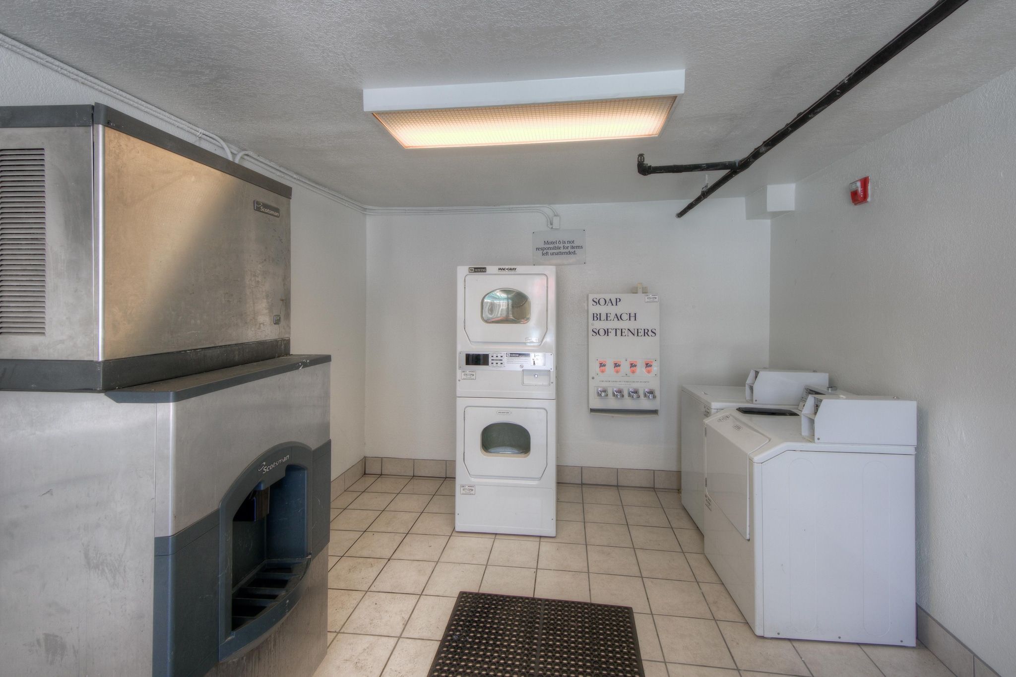 A laundry room with a washing machine, dryer, and a sign indicating soap and bleach softeners.