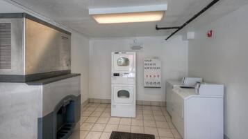 A laundry room with a washing machine, dryer, and a sign indicating soap and bleach softeners.