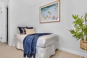 A bedroom with a bed, a painting, and a potted plant. - Colley Reserve Retreat (Glenelg)