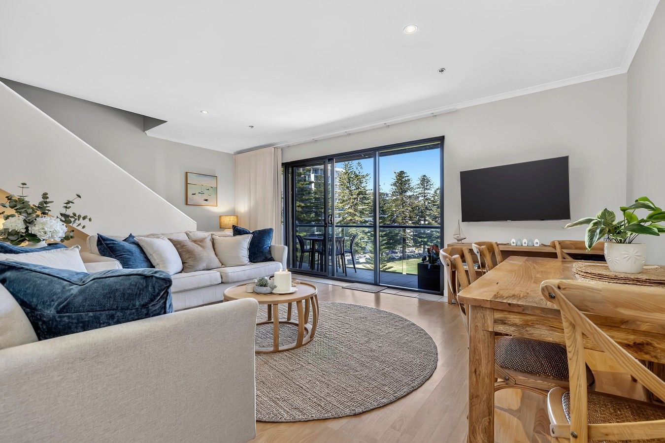 A modern living room with a sofa, coffee table, and dining area.