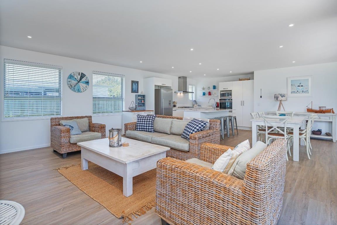 A modern living space with wicker furniture, a kitchen area, and a dining table.