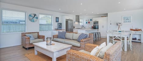 A modern living space with wicker furniture, a kitchen area, and a dining table.