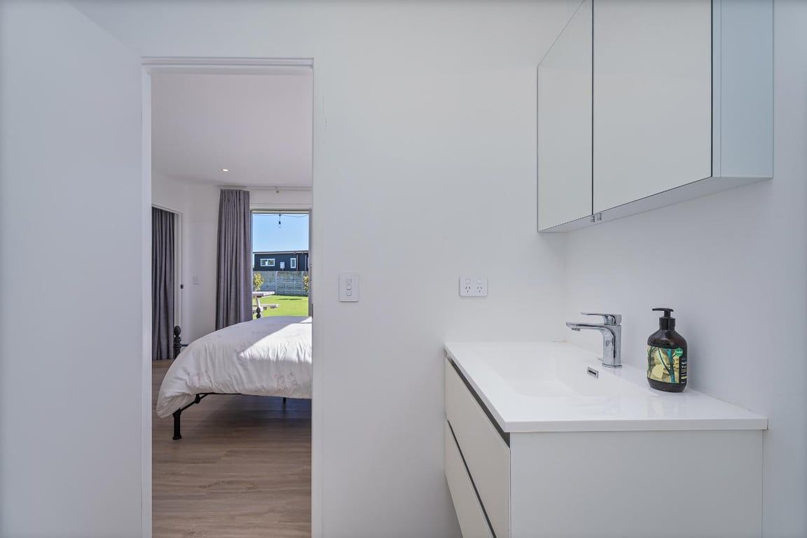 Een moderne badkamer met een witte wasbak, een spiegel en een zeepfles.
