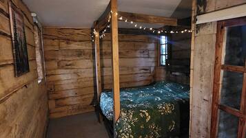 Une chambre avec un lit à baldaquin, des murs en bois, une fenêtre et des guirlandes lumineuses.
