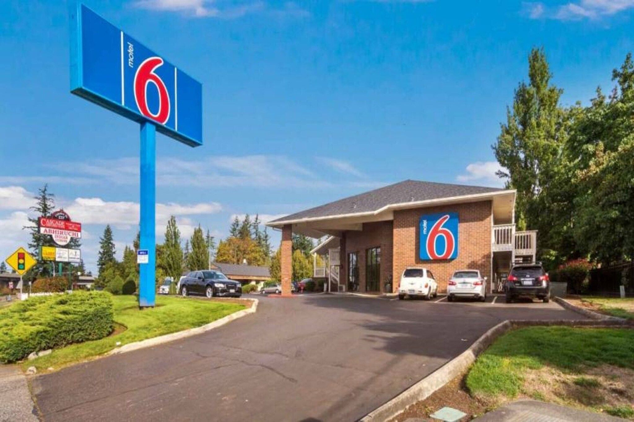 A motel with a prominent '6' sign, a parking lot, and a few cars parked in front.