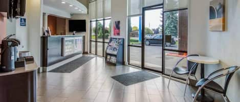 A reception area with a counter, a seating area with chairs, and a large glass door leading outside.