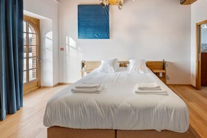 Ein Hotelzimmer mit einem großen Bett, einem Holzkopfstück und Blick ins Freie durch ein Fenster.