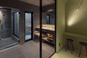 Une salle de bain moderne avec une douche à parois de verre, un meuble-lavabo avec un miroir et deux tabourets.