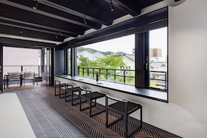 A modern interior with a long bar area, seating, and large windows offering a view of buildings and greenery. - HITOTOSE HARU -Kyoto Gion Shirakawa- (Kyoto)