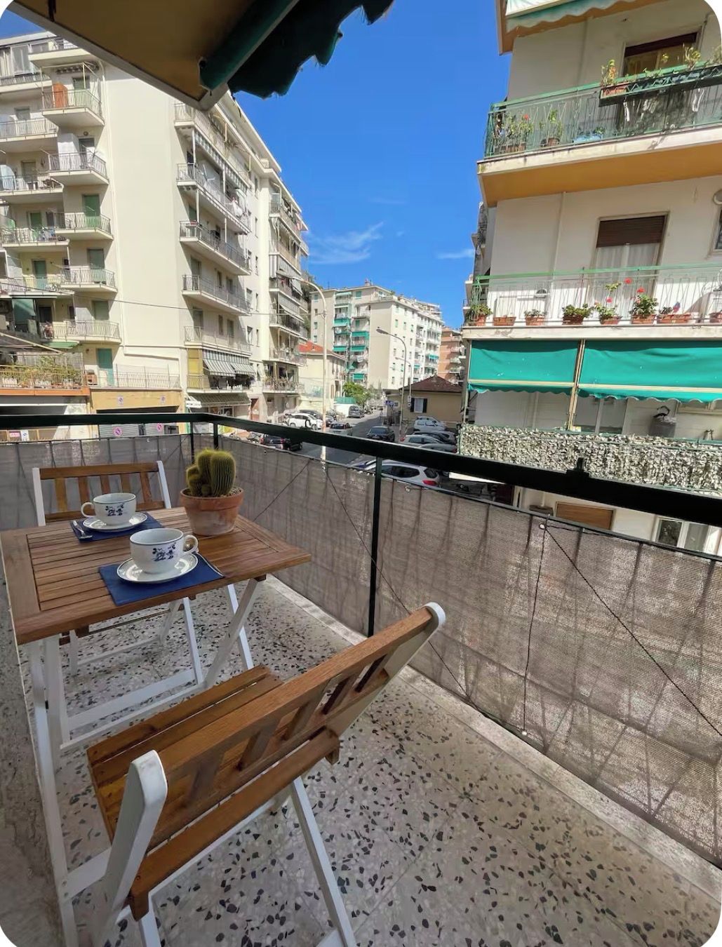 A balcony with a table set for two, a chair, and a potted plant.