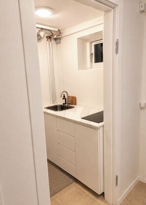 A compact kitchen with a sink, a window, and a door leading to another room. - Spacious & Cozy Apartment in Copenhagen (København)