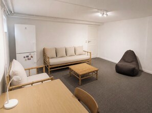 A room with a sofa, a chair, a table, a lamp, a small stool, and a dark bean bag. - Spacious & Cozy Apartment in Copenhagen (København)